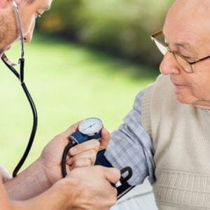 An healthcare provider taking the blood pressure of an elderly man