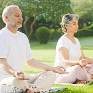 The image portrays a senior citizen practicing meditation in a serene environment.
